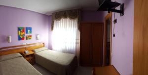 a small bedroom with two beds and a window at Hostal Restaurante Carolina in Pedrosillo el Ralo