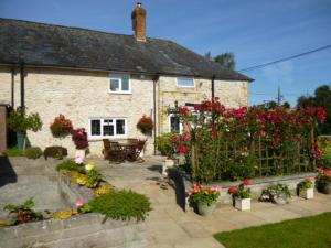 a garden in front of a house with flowers at Quiet Woman House in Halstock