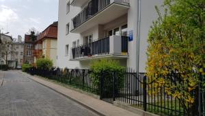 un edificio blanco con una valla negra al lado de una calle en StudioSpanie Sopot beach rooms, en Sopot