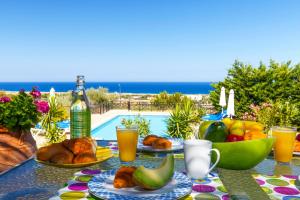 Villa Alexi في كالاثوس: طاولة مليئة بأطباق الطعام والمشروبات بجوار حمام سباحة