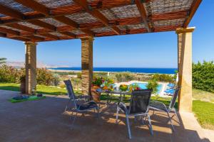 a patio with a table and chairs and a view of the ocean at Villa Alexi in Kalathos