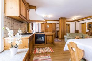 a kitchen with wooden cabinets and a living room at Appartamenti Al Bivio in Imer