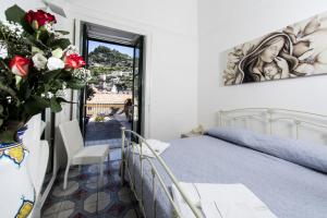 1 dormitorio con 1 cama y un jarrón con rosas en Antica Dimora Romana, en Minori
