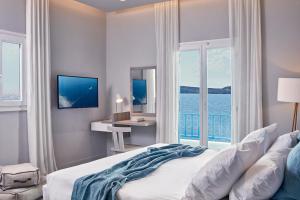 a bedroom with a bed with a view of the ocean at Poseidon of Paros Hotel & Spa in Chrissi Akti
