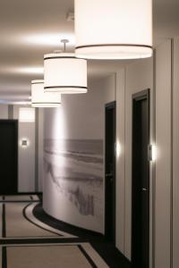 a hallway with two lights and a picture of the ocean at Hotel Am Leuchtturm in Warnemünde