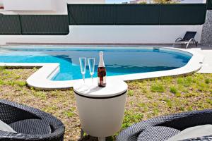 a bottle of wine sitting on a table next to a swimming pool at Villa Monaco in Faro