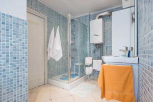 La salle de bains est pourvue de carrelage bleu, d'une douche et d'un lavabo. dans l'établissement Apartment M49, à Zagreb