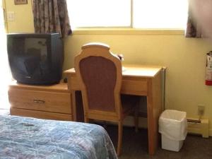 1 dormitorio con escritorio, TV y cama en Auberge Mountain View Inn, en Mont-Tremblant