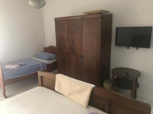 a small room with a bed and a cabinet and a tv at Hill House Marija in Komiža