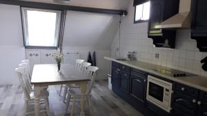 cocina con mesa, sillas blancas y fregadero en Noord-Hollands Hof Dream, en Spijkerboor