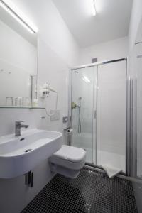 a bathroom with a toilet and a sink and a shower at Hotel White Lion in Prague