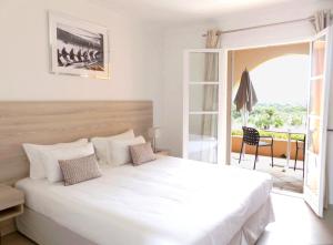 a bedroom with a large white bed and a balcony at Hôtel les Bouis - Vue mer in Saint-Tropez