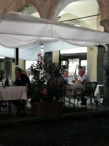 un grupo de personas sentadas en mesas en un restaurante en La via per Milano, en Vigevano