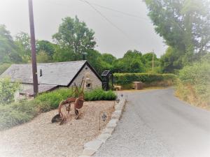 a house on a road next to a road withanimal statues at The Bakery in Llanddeiniol +34 photos