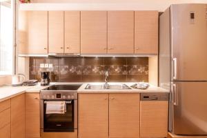 une cuisine avec des armoires en bois et un réfrigérateur en acier inoxydable dans l'établissement Kantouni Bizi Myranthis Apartment, à Corfou 5 autres photos