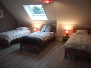 a attic bedroom with two beds and a skylight at Gite Les Gobelins in Paimpont