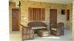 un patio con sillas de mimbre, un banco y una pared de ladrillo en Chalés 4 Estações en Beberibe