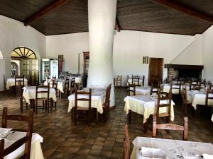 un comedor con mesas blancas y sillas de madera en Hotel Su Meriagu, en Capitana