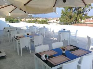 a restaurant with white tables and white chairs and an umbrella at Ege Birlik Boutique in Aydın