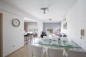 a dining room with a glass table and white chairs at Pallinio Fig Tree Bay Apartments in Protaras