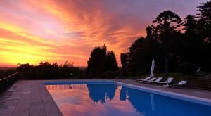 a pool with chairs and a sunset in the background at Quinta de Sao Thiago in Sintra
