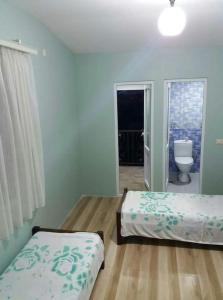 a bedroom with two beds and a bathroom with a toilet at Guest House TiAni in Kobuleti