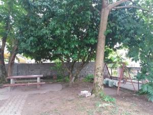 a park with a bench and a swing under some trees at Guest House TiAni in Kobuleti