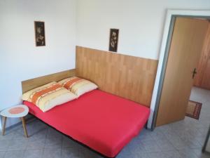 a bed in a room with a red bedsheet at Apartmani Parlov in Vinišće