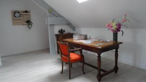 un escritorio de madera con una silla y un jarrón de flores en Chambres d'hotes Maison Gille, en Nuits-Saint-Georges