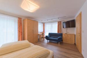 a bedroom with a bed and a couch and a television at Haus Rosmarie in Sankt Anton am Arlberg