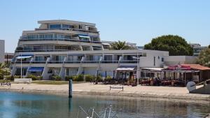 un edificio con tavoli e ombrelloni accanto a un corpo d'acqua di Rivages d'Ulysse Port Camargue a Le Grau-du-Roi