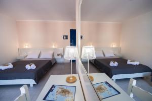 a room with two beds and a table with a lamp at Akroyiali Resort in Vasiliki