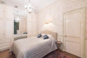 a white bedroom with a bed and a chandelier at Veeve - Antique Charm by Arc de Triomphe in Paris