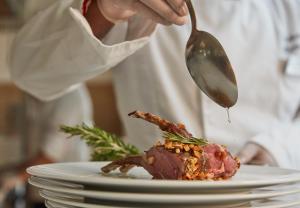 a chef is serving food on a plate with a spoon at VOI Marsa Siclà Essentia in Sampieri
