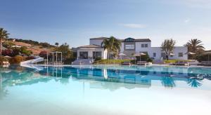 a swimming pool with blue water in front of a house at VOI Marsa Siclà Essentia in Sampieri