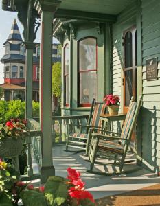 een veranda met stoelen en een tafel op een huis bij The Queen Victoria in Cape May