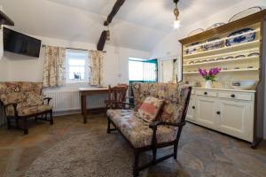 a living room with two chairs and a kitchen at Cissy's Cottage - traditional thatched cottage, on the Causeway Coast in Aghanloo