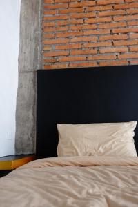 a bed with a black headboard and a brick wall at Black Elephant Boutique in Surat Thani