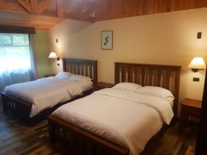 Un dormitorio con dos camas y una ventana. en Casa El Granero Monteverde, en Monteverde