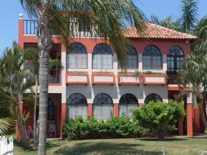 un edificio rojo y blanco con palmeras delante en La Alhambra Apart Hotel, en Florianópolis