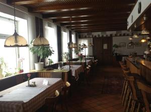 un comedor con mesas, sillas y ventanas en Witt's Gasthof, en Krummbek