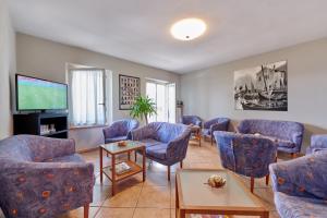 sala de estar con sillas azules y TV de pantalla plana en Albergo Del Garda, en Torri del Benaco