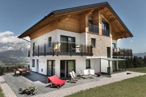 Casa grande con balcón con sillas rojas. en Appartements Almnest en Schladming