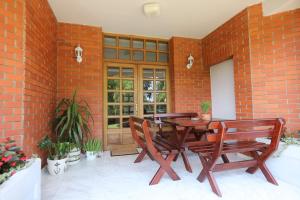 a patio with a wooden table and chairs and a brick wall at Vila LOLA in Bela Crkva