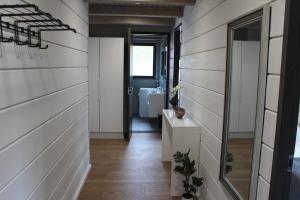 a hallway with white wood paneled walls and a mirror at Naava Chalet Lumi 301 in Ähtäri +2 photos