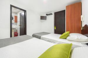 two beds in a hotel room with green pillows at Hotel Bogotá Chapinero in Bogotá