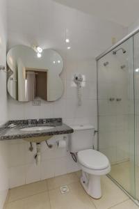a bathroom with a toilet and a sink and a mirror at Canasvieiras Hotel in Florianópolis