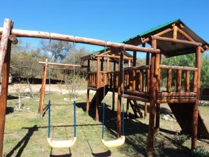 un parque infantil de madera con columpios en Cabañas Señales en San Marcos Sierras