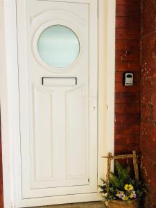 a white door with a window and a basket of flowers at Whiteley's Cottages in Dumbarton