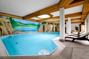 a swimming pool with a mural on the wall at Holzschuhs Schwarzwaldhotel in Baiersbronn
